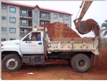 Truck and excavator carrying out earthworks on a project site in Awka